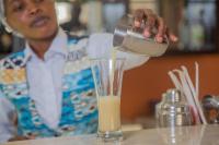 a man pouring an orange juice into a glass at Hôtel La Rose Blanche Abidjan in Abidjan