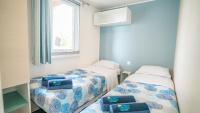 A bed or beds in a room at Happy Camp Mobile Homes in Camping Cisano San Vito