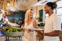 Van der Valk Plaza Beach & Dive Resort Bonaire - ALL INCLUSIVE في كراليندايك: رجل وامرأة يمسكان صحن طعام