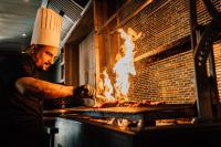 Van der Valk Plaza Beach & Dive Resort Bonaire - ALL INCLUSIVE في كراليندايك: رجل يطبخ الاكل في فرن