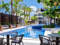 Una piscina al aire libre con mesas, sillas y palmeras. en seven x seven ISHIGAKI, en Ishigaki Island