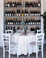 une table avec des chaises blanches et des bouteilles de vin dans l'établissement Villa Maria Luigia, à San Biagio di Callalta