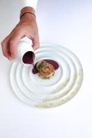 una mano sosteniendo un plato blanco con un postre en Fleur de Loire, en Blois