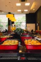 Una línea de buffet con grupos de comida en cuencos rojos. en ibis budget BH Afonso Pena Savassi, en Belo Horizonte