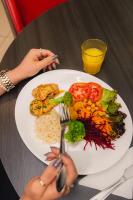 una persona sosteniendo un tenedor y un plato de comida en ibis budget BH Afonso Pena Savassi, en Belo Horizonte