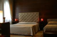 a bedroom with two beds and two lamps and a window at Hotel Abbazia in Venice