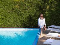 Una mujer está de pie junto a una piscina. en Mercure Paris Sud Les Ulis-Courtaboeuf, en Les Ulis