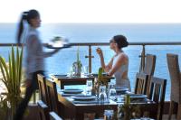 una donna che mangia a un tavolo su un balcone di Blue Bay Resort Hotel ad Agia Pelagia