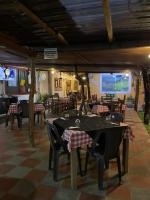 een restaurant met tafels en stoelen en een groot scherm bij Casa y Restaurante- Pizzeria La Pergola in Tonsupa