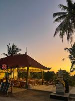 a building with a restaurant with a sunset in the background at Palma House Kelingking in Nusa Penida