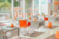a dining room with tables and chairs with orange napkins at HARRIS Hotel Batam Center in Batam Center
