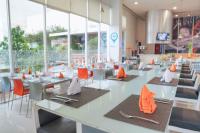 a dining room with tables and chairs with orange napkins at HARRIS Hotel Batam Center in Batam Center
