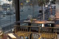 Un restaurante con dos mesas y sillas y una ventana. en Petit Hotel, en Milazzo