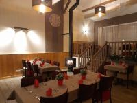 Un restaurante con mesas y sillas y un reloj en la pared. en Les pierres roses, en Coise