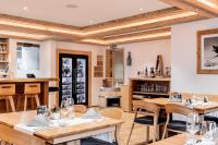 LenzVal Saraina Apartments的有木桌椅和酒吧的餐厅