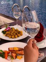 una persona sosteniendo una copa de vino junto a platos de comida en Hoang Yen Boutique Hotel, en Dien Ban