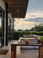 eine Terrasse mit Holztischen und Bänken auf einem Gebäude in der Unterkunft Zenery Lake Resort in Ban Don Klang
