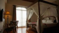 a bedroom with a canopy bed with a chair and a desk at LivingGreen B&amp;B in Luodong