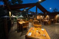 un restaurante con mesas y sillas de madera por la noche en Emma Gorge Resort at El Questro, en Kununurra