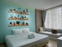 a bedroom with a bed and a window with plants on shelves at Beat Hotel Bangkok in Bangkok