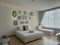 a white bedroom with a bed and a couch at Beat Hotel Bangkok in Bangkok