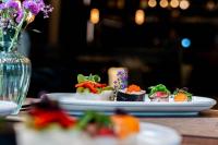 Un plato de sushi en una mesa con un jarrón de flores. en Hotel Das Zeit, en Lenzing