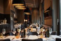 uma sala de jantar comprida com mesas, cadeiras e copos em The George Hamburg em Hamburgo