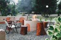 Una fogata en un patio con sillas y troncos. en Sribudaya Resort, en Payaarp