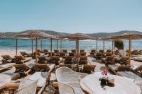 a beach with chairs and tables and umbrellas at Coralli Seaside Resort in Livadakia