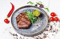 een biefstuk op een blauw bord met tomaten en kruiden bij Полінарія Козятин in Kozyatyn