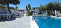 a swimming pool with tables and chairs next to a building at Skiathos Holiday Resort in Skiathos
