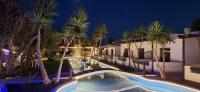 a swimming pool in front of a building with palm trees at Skiathos Holiday Resort in Skiathos