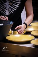 a person holding a bowl over yellow plates at La Maison Clémenceau in Salon-de-Provence