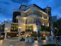 Un gran edificio blanco con algunas mesas delante. en Garden Boutique Hotel, en Elbasan