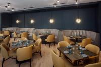 Un restaurante con mesas y sillas en una sala. en The Heartwood, en Poughkeepsie