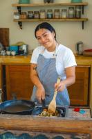 eine Frau in einer Küche, die Essen in einer Pfanne zubereitet in der Unterkunft Casa Mia El Cuyo Eco Beach Boutique Hotel in El Cuyo