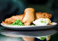 een bord met vis en erwten op tafel bij Invergarry Hotel in Invergarry