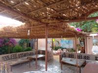 a patio with benches and a straw roof at "Par 4 Chemins" - Atypical stopover in Nouakchott