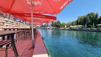 rząd stołów z parasolami i rzeką w obiekcie Hotel Luciano w mieście Struga
