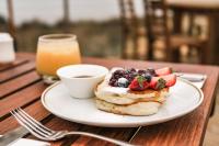 Un plato de panqueques con fruta y una taza de café. en Panorama Hotel St Helens, en St Helens