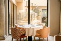 una mesa en una habitación con sillas y una mesa con copas de vino en La Maison d'Uzès Relais & Châteaux, en Uzès