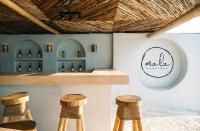 een bar met drie barkrukken voor een toonbank met wijnflessen bij Mala Boutique Hotel in Bwejuu
