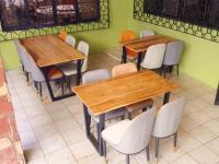 a restaurant with wooden tables and white chairs at Olivia Guesthouse in Mwanza