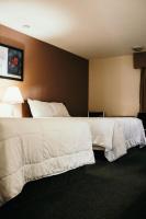 フォート・ネルソンにあるThe Fort Hotelの白いシーツが敷かれたベッドが2つあるホテルの部屋