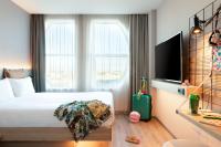 a bedroom with a white bed and a flat screen tv at Moxy The Hague in The Hague