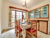 een eetkamer met een tafel en stoelen en een raam bij mahin cottage in Manāli