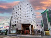 Un edificio alto y blanco en una calle de la ciudad. en APA Hotel Takaoka Marunouchi, en Takaoka
