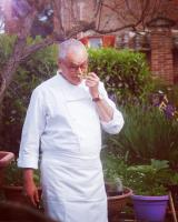 een oudere man staat in een tuin en rookt een sigaret bij Agriturismo La Terra in Valiano