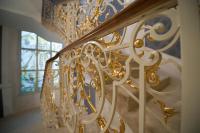 a gold chandelier on a staircase with a window at Wilson Palace by LOFT in Bratislava