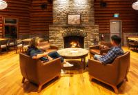 Un grupo de personas sentadas en sillas en una sala de estar con chimenea. en The Lodge at Bow Lake, en Lago Louise